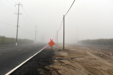 Road caution sign in a foggy day