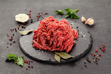 Raw meat products. Veal or mixed homemade minced meat with spices on a black background. board...