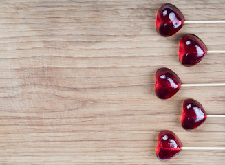 Jelly marmalade red cherry hearts on a wooden stick on a wooden background