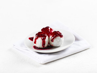 Cottage cheese balls with black currant berry sauce on a light background