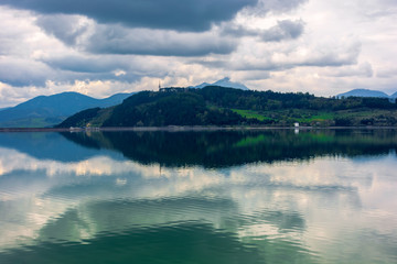 Naklejka premium lake liptovska mara in slovakia. wondeful travel destination of high tatras mountain ridge. cloudy weather in springtime. reflection in the water