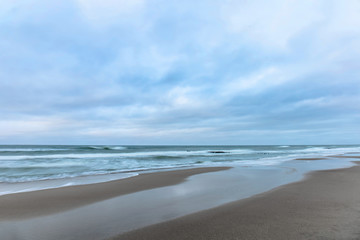 Fototapeta na wymiar landscape of wide sandy beach by the cold Baltic sea in cloudy weather at long exposure