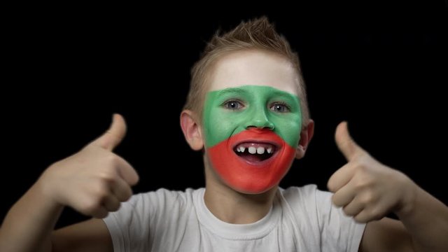 Happy boy rejoices victory of his favorite team of Hungary. A child with a face painted in national colors. Portrait of a happy young fan. Joyful emotions and gestures. Victory. Triumph.