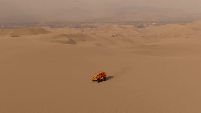 Dune buggy. Sandy desert oasis lake. DRONE. Adventure Dune Buggy. Speed. Tourism shot in Huacachina, Peru. Epic, Fast. Water in middle of hot sand desert. Romantic, holiday, honeymoon, scenic shot.