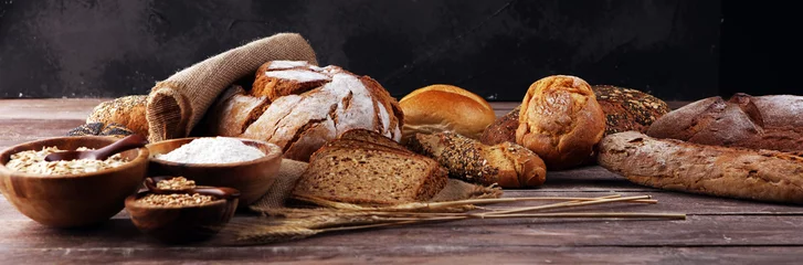 Wall murals Bread Assortment of baked bread and bread rolls and cutted bread on table background