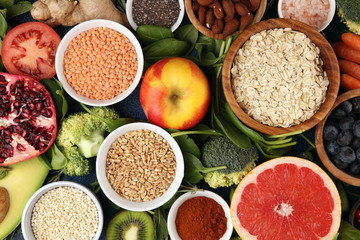 Healthy food clean eating selection: fruit, vegetable, seeds, superfood, cereals, leaf vegetable on rustic background