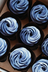 Decoration with blue purple cream muffins. Cooking chocolate cream cupcakes. Confectioner cooks in kitchen.