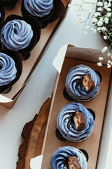 Decoration with blue purple cream muffins. Cooking chocolate cream cupcakes. Confectioner cooks in kitchen.