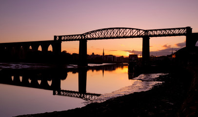 Fototapeta na wymiar Orange and purple sunset on the town of Drogheda through the Boyne Viaduct seen from river banks