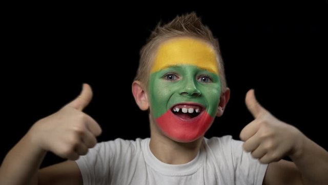 Happy boy rejoices victory of his favorite team of Lithuania. A child with a face painted in national colors. Portrait of a happy young fan. Joyful emotions and gestures. Victory. Triumph.