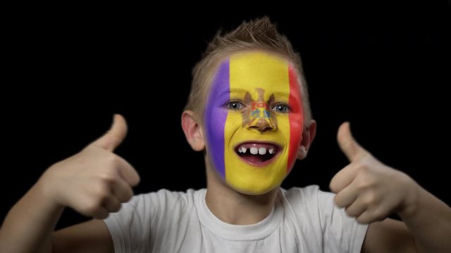 Happy boy rejoices victory of his favorite team of Moldova. A child with a face painted in national colors. Portrait of a happy young fan. Joyful emotions and gestures. Victory. Triumph.
