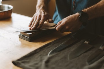 Person sharpening knives with a whetstone in the kitchen