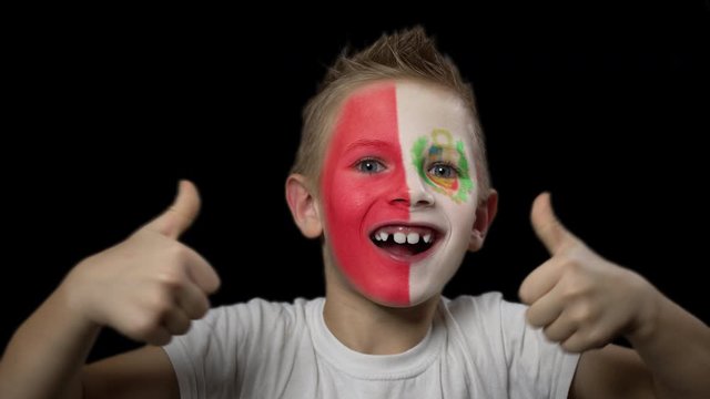 Happy boy rejoices victory of his favorite team of Peru. A child with a face painted in national colors. Portrait of a happy young fan. Joyful emotions and gestures. Victory. Triumph.