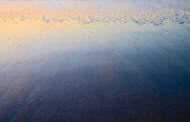 Sunset glow reflections in wet sand, evening mood at a beach.
