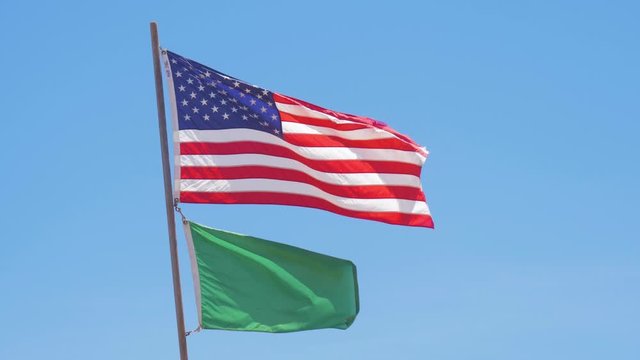 Waving flag of the United States of America with green beach flag under the Stars and Stripes