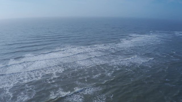 Aerial photo of the waves coming ashore. Multiple lines of waves are breaking on the ocean.