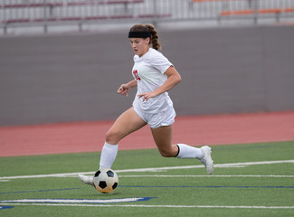 Fototapeta premium Young athletic girl playing in a soccer match