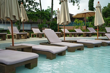 Exterior architecture and swimming pool design of resort and spa private villa hotel decorated with natural ecology furniture and outdoor sunbathing daybed 