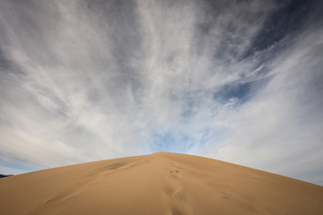 Fototapeta na wymiar Crest of Sand Dune and Cloudy Sky