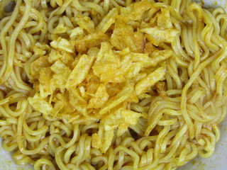 flat lay Close up  eat hot cooked fresh warm wavy textured red yellow brown gold color of mie mee goreng or fried noodle with potato chip krupuk kripik crackers new creation. thick like hair heap pile