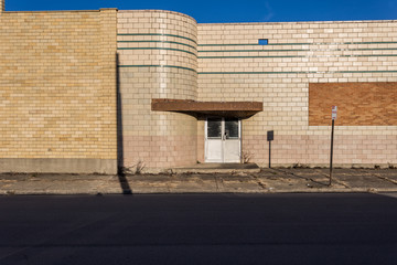 Locked entrance to an abandoned retail building with bricked over windows and rounded corners