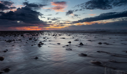 Water washes over pebbles along the coast in a long exposure shot of the tauranga harbour