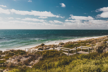 view of Cottesloe beach near Perth with thick vegetations and staircases leading to the sandy shore