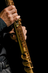 soprano saxophone in hands on a black background