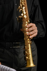 Naklejka premium soprano saxophone in hands on a black background