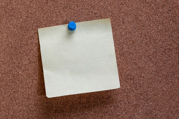 blank note on cork board, blue thumbtack holding sticky note to memo board