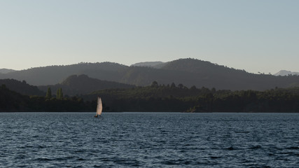 Obraz premium Beautiful boat sailing the calm and quiet Lake Alumine during the sunset golden hour