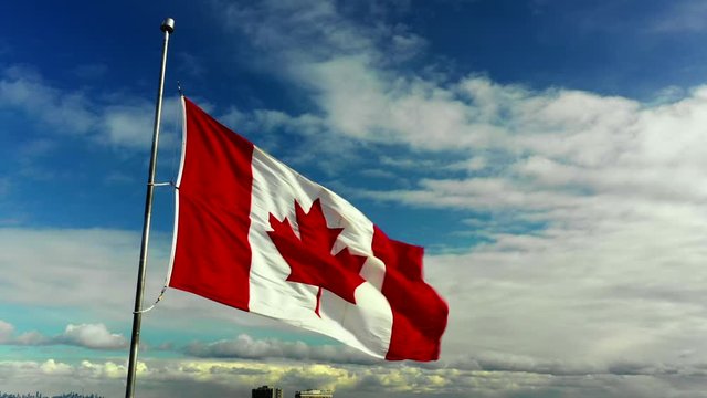 Canadian Flag flailing on a cloudy blue sky