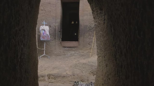 Forward push-in through tunnel to reveal entrance of the Bet Medhane Alem rock-hewn church in Lalibela, Ethiopia