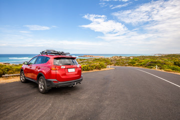 Fototapeta na wymiar Red car parked in scenic spot along ocean drive in South Australia