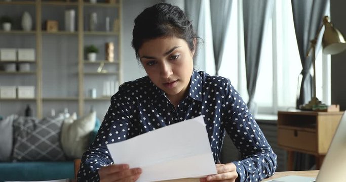 Frustrated indian girl feeling upset reading bad news in letter