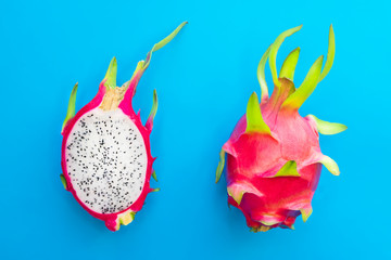 Dragon fruit, 2 two ripe pitaya or exotic tropical pitahaya, sweet cactus cut in half and whole fruit on blue background. Top view. Summer, healthy fresh food, vegan or vegetarian diet concept.
