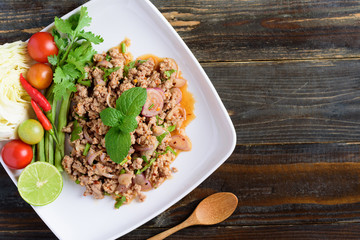 Thai food, spicy minced pork salad (Larb Moo) and spoon on wooden background