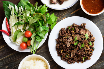 Northern Thai food, spicy minced pork salad (Larb Moo Kua) eating with fresh vegetables and sticky rice, Top view