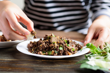 Northern Thai food, spicy minced pork salad (Larb Moo Kua) eating with sticky rice by hand