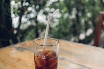 Glass of soda with a white straw on table.
