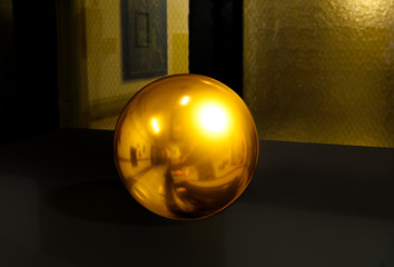 3d sphere on black table background texture with shadow. Crystal shape or realistic glass ball in gold metal. 3D render modern room. Abstract glossy bubble. Used for banner and new poster on website.