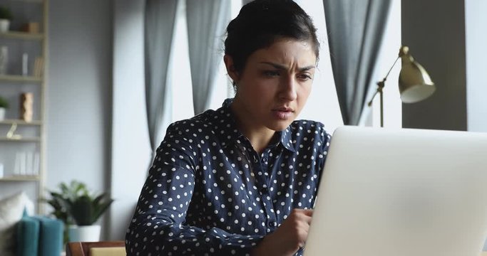 Indian woman looking at laptop frustrated after reading bad news