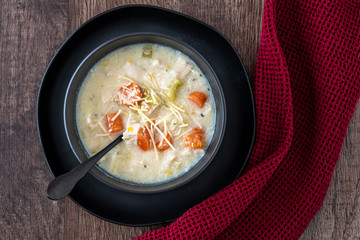 Greek lemon rice soup in a black bowl and black plate, black spoon and red napkin, rustic wood table