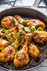 Roasted chicken legs in pan with herbs - close up