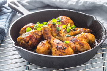 Roasted chicken legs in pan with herbs - close up
