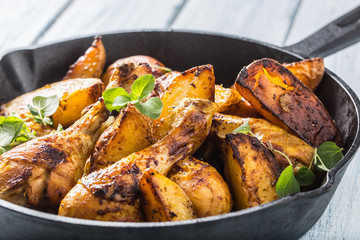 Roasted chicken legs in pan with american potatoes and herbs