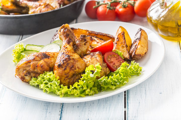 Roasted chicken legs with lettuce salad and tomatoes