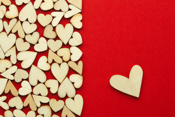 Romantic background of dozens of tiny wooden hearts with a single heart on a red card. For love,...