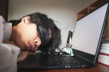 Young man sleeping in front of laptop computer.