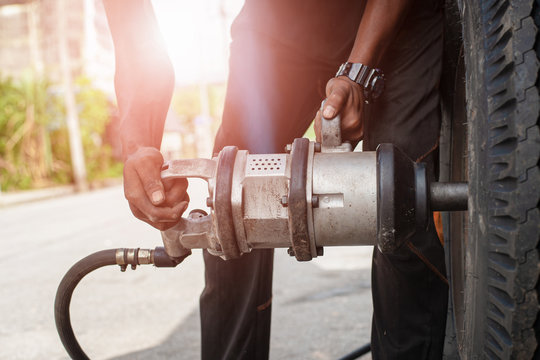 Hands of mechanic changing car wheel in auto repair service with pneumatic gun